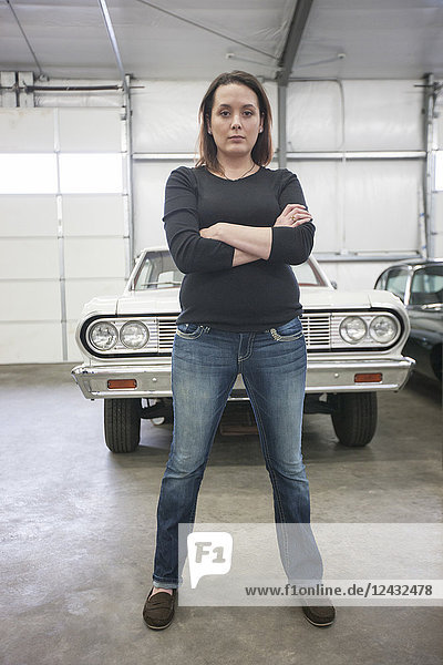 A portrait of a Caucasian female mechanic in a car repair shop.