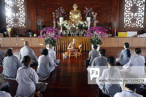A teacher instructs a group of people how to recite Buddhist chants  Minh Dang Quang Buddhist Temple  Ho Chi Minh City  Vietnam  Indochina  Southeast Asia  Asia