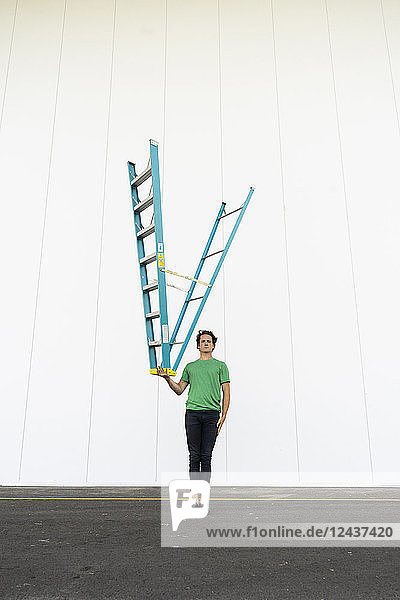 Acrobat balancing ladder upside down in his hand