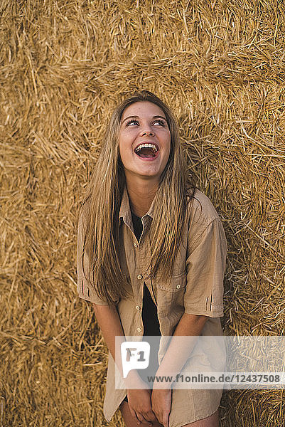 Laughing young woman standing in front of hay bales  portrait