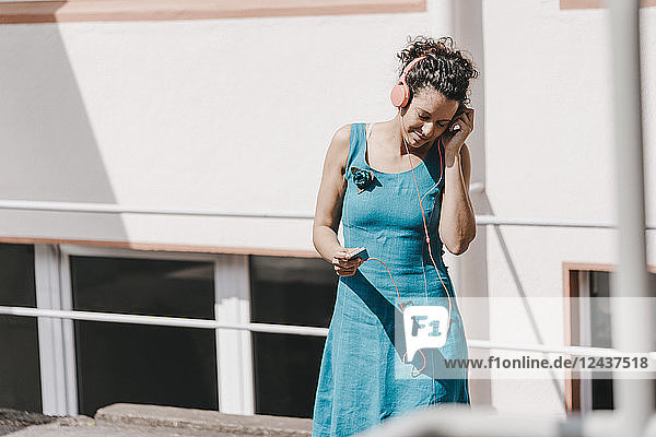 Woman standing in backyard wearing headphones listening music