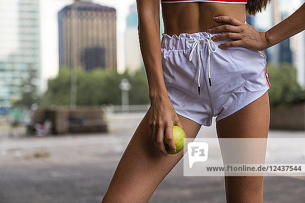 Close-up of young woman wearing gym shorts holding an apple