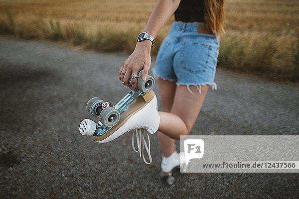 Young woman with roller skates on country road  partial view