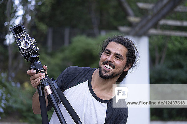 Portrait of happy young man with vintage camera