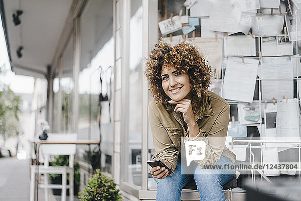 Woman in front of coffee shop  holding smart phone