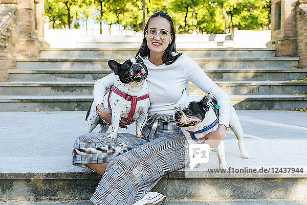 Portrait of woman sitting in the park with her two dogs