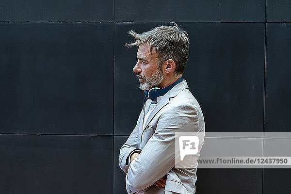 Bearded businessman with headphones in front of black wall