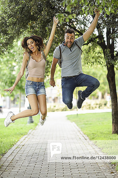 Carefree couple jumping in park