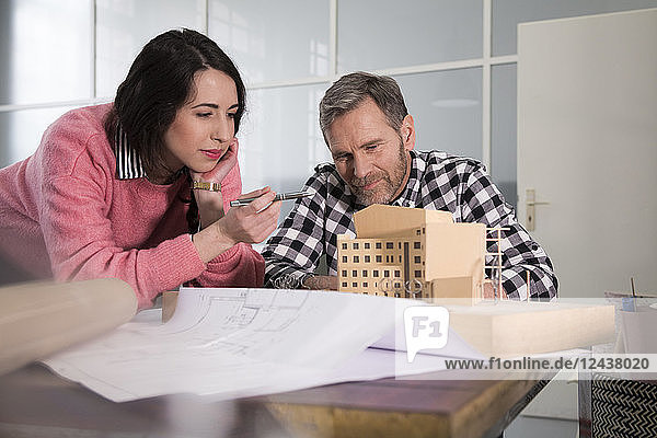 Colleagues examining architectural model in office