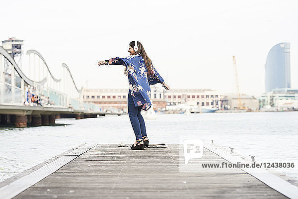 Spain  Barcelona  happy young woman with headphones dancing on jetty