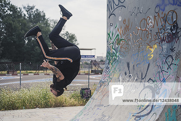 Tattooed man doing parkour in a skatepark