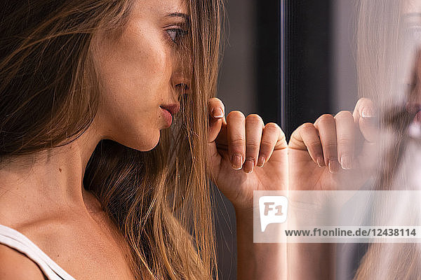Serious attractive young woman leaning against glass pane