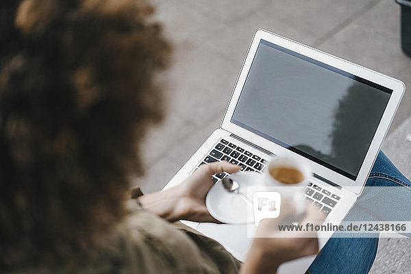 Woman using laptop  drinking coffee