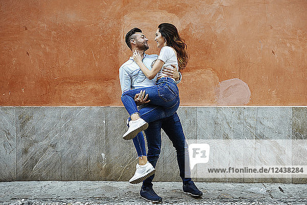 Carefree couple in love in front of a wall outdoors