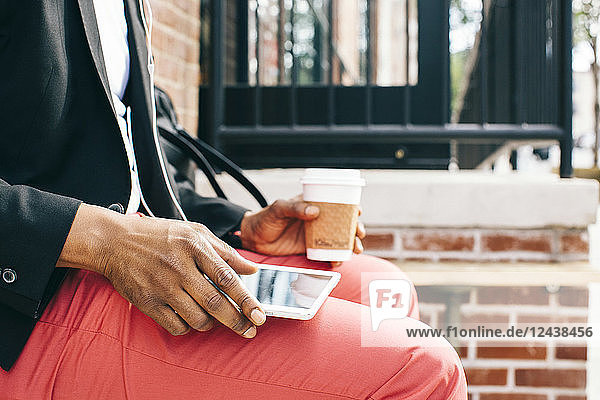 Man sitting in the street  using digital tablet  drinking coffee