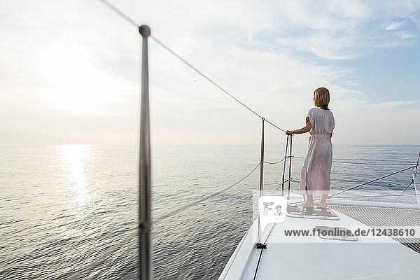 Mature woman standing on catamaran  watching sunset