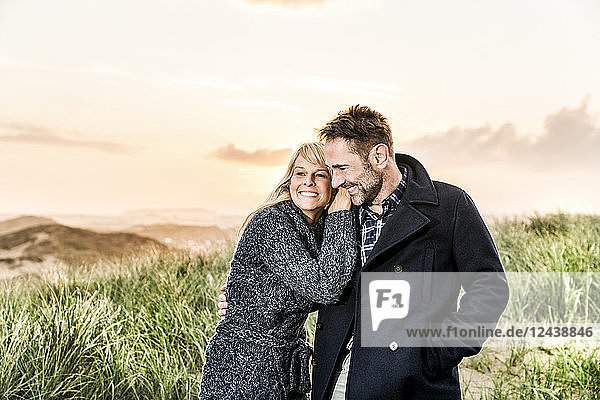 Happy couple in dunes at sunset