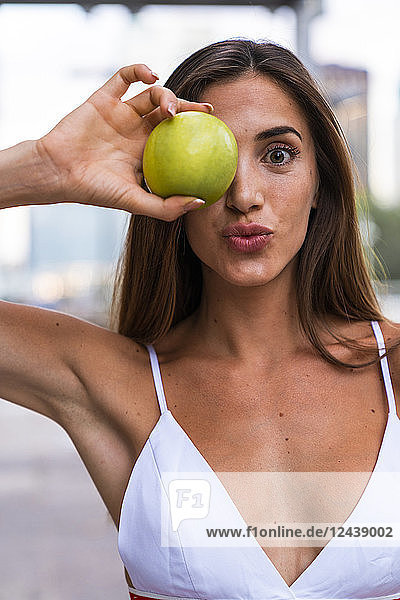Portrait of attractive young woman wearing sports bra holding an apple