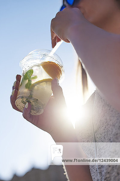 Woman drinking lemonade from plastic cup  close-up