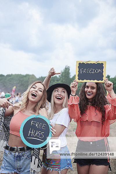 Happy women at the music festival with signs  free hugs  freedom