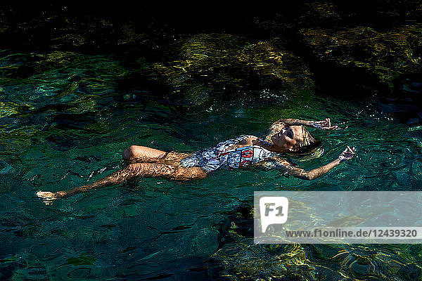 Young woman floating on water in lagoon