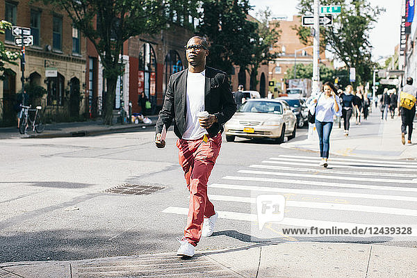 USA  NYC  Brooklyn  Man walking in the street  holding cup of coffee