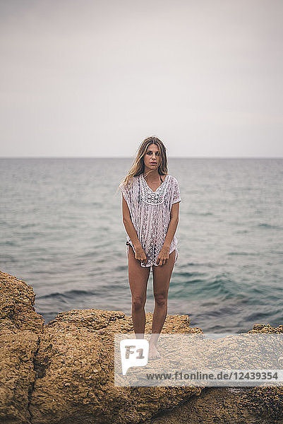 Portrait of young woman standing on a rock at the coast