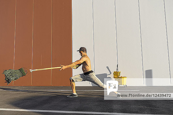 Acrobat playing with cleaning bucket and mop