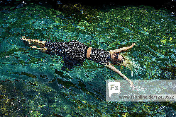 Young woman floating with dress on water in lagoon