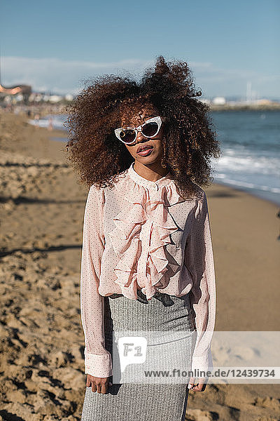 Portrait of beautiful young woman with afro hairdo standing on the beach