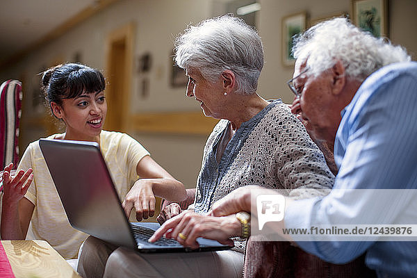 Nurse teaching seniors in retirement home  how to use laptop