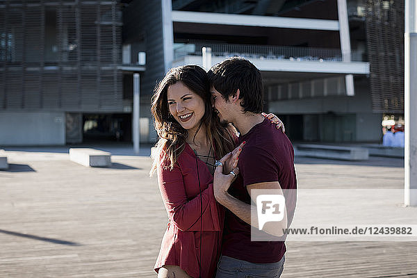 Happy affectionate young couple standing on city square