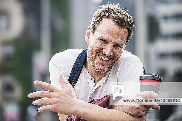 Portrait of happy man with takeaway coffee in the city