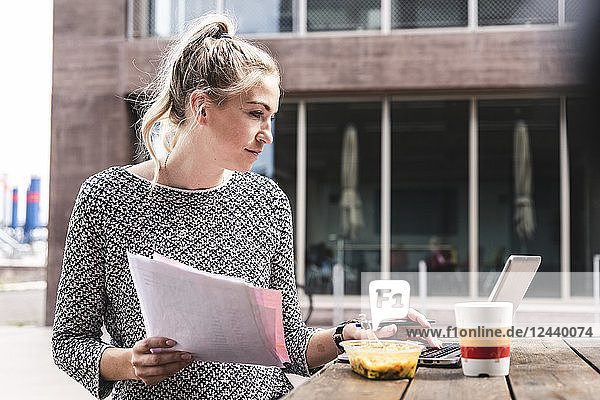 Young buisinesswoman sitting outdoors working and having lunch