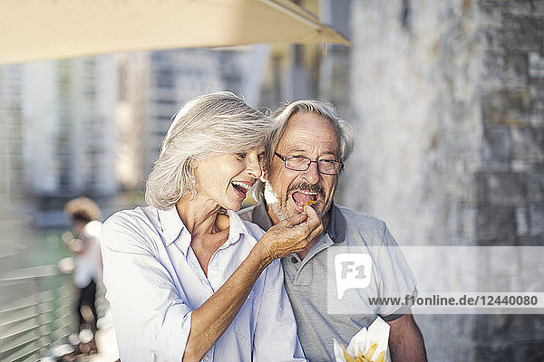 Senior couple taking a city break  eating French fries