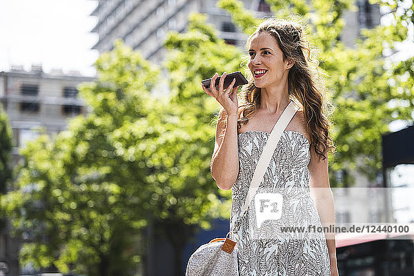 Smiling woman using cell phone in the city