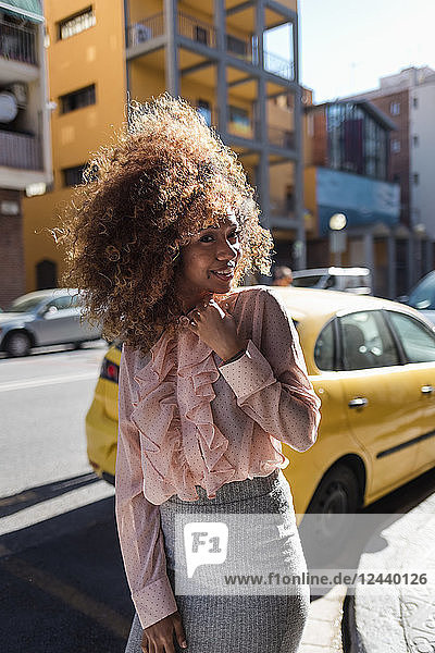 Portrait of smiling beautiful young woman with afro hairdo in the city