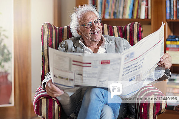 Senior man sitting in library  reading newpaper