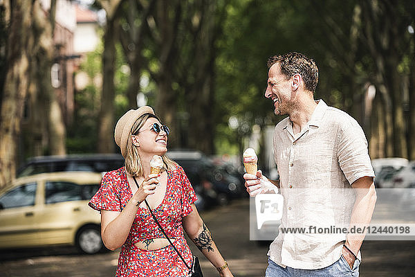Happy couple with ice cream cones walking in the city