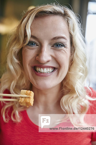 Portrait of happy blond woman eating tofu