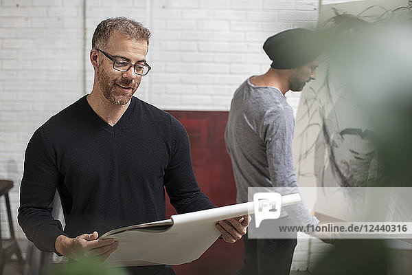 Smiling man looking at sketchbook in artist's studio