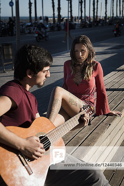 Spain  Barcelona  couple with a guitar sitting on a bench at seaside promenade