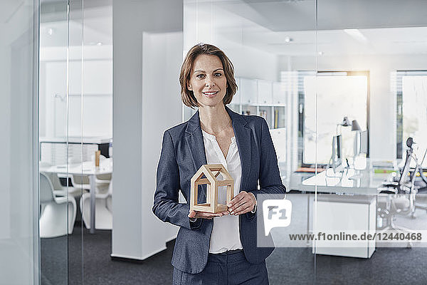 Portrait of smiling businesswoman holding architectural model in office