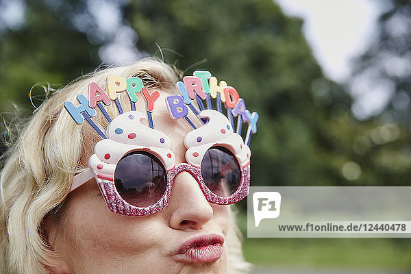 Woman pouting wearing birthday eyeglasses