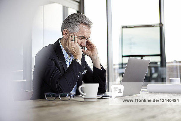 Businessman with headaches sitting at desk in office