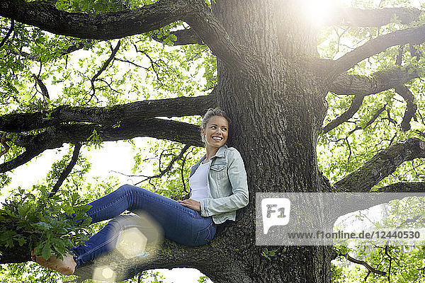 Smiling woman sitting on branch relaxing