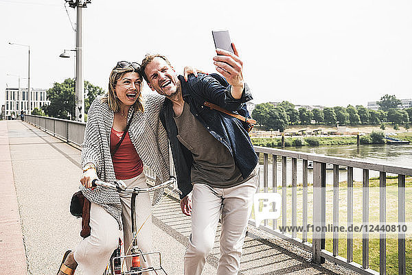 Happy couple taking a selfie on a bridge