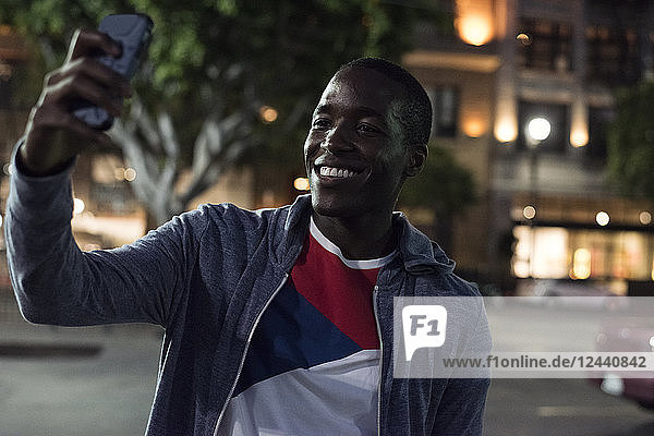 Smiling young man taking a selfie at night