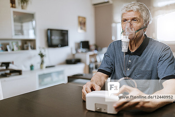Senior man using inhaler at home