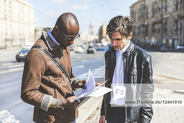 Russia  Moscow  two businessmen looking at documents in the city